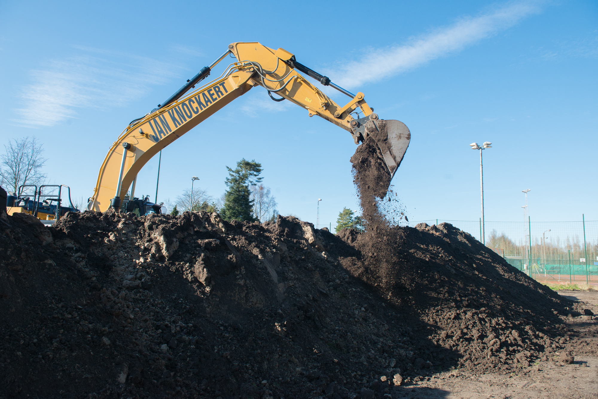 Graafkraan stort grond op een berg teelaarde