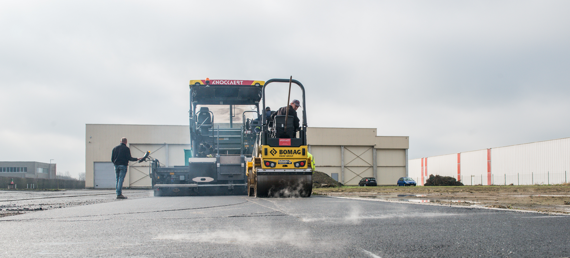 Asfaltafwerkmachine en wals op een industrieterrein