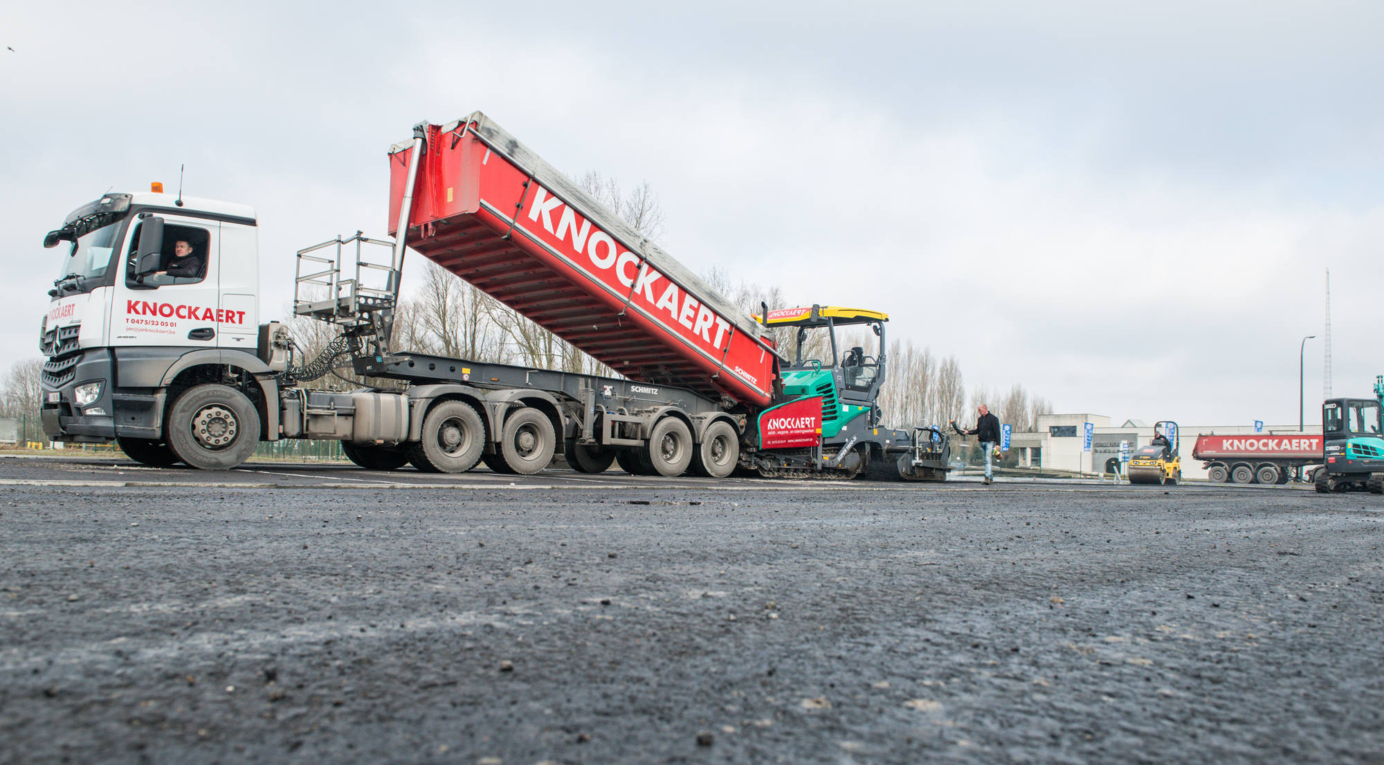 Knockaert-vrachtwagen kipt asfalt in de afwerkmachine